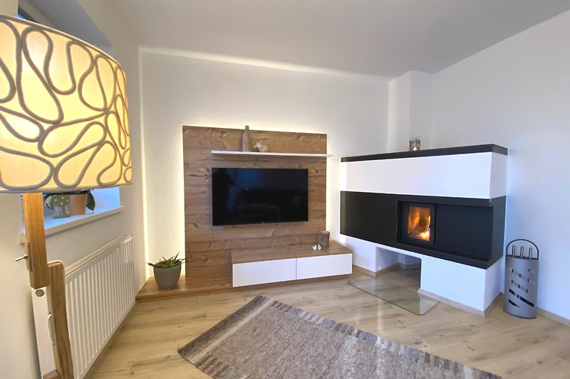 Wohnzimmer mit Holzboden, Kamin und Fernseher. Gemütliche Atmosphäre.
