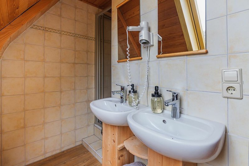 Schönes Badezimmer mit lila Waschbecken, Spiegel und Holzboden.