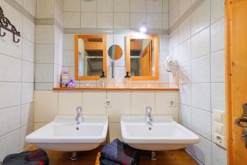 Spiegel, Waschbecken und lila Blume in einem Badezimmer.