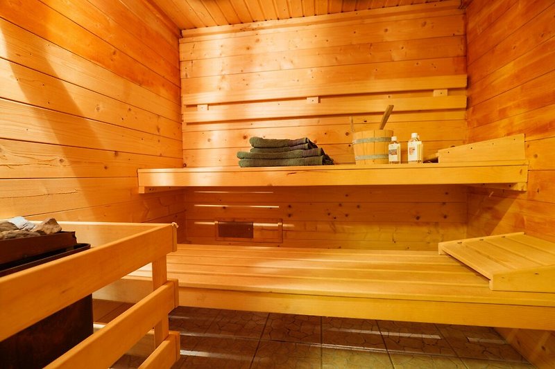 Schöne Holzverkleidung und rustikale Balken in gemütlicher Sauna.