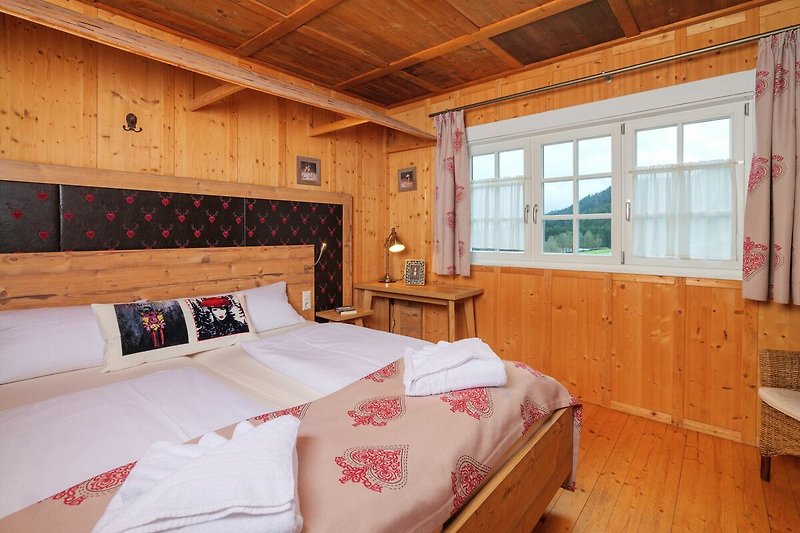 Gemütliches Schlafzimmer mit Holzbett, Fenster und gemütlicher Einrichtung.