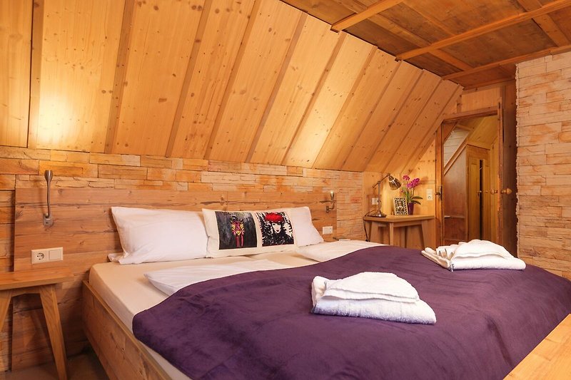 Komfortables Schlafzimmer mit Holzbett, Lampen und Pflanzen.