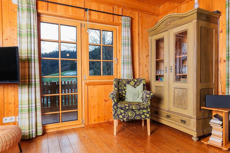 Gemütliches Wohnzimmer mit Holzmöbeln und Fensterdekoration.