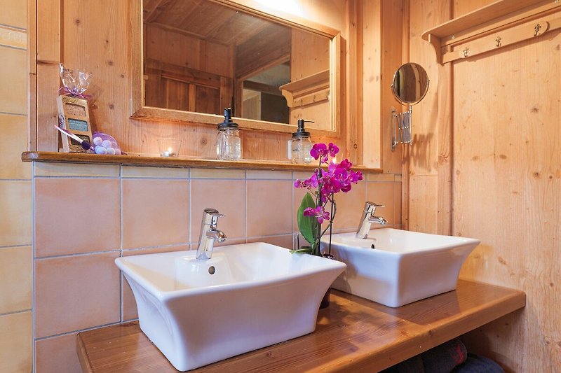 Schönes Badezimmer mit braunem Holz, Spiegel und Pflanze.