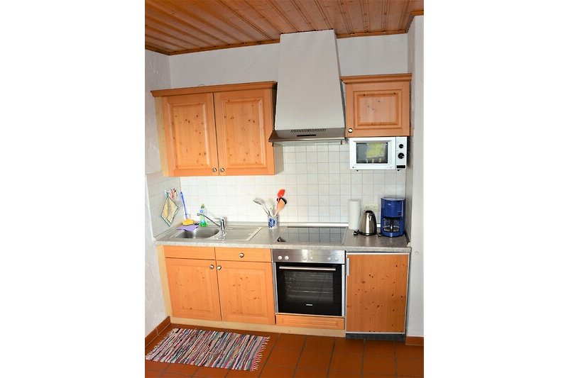 Moderne Küche mit Holzakzenten, Edelstahlgeräten und Fensterblick.