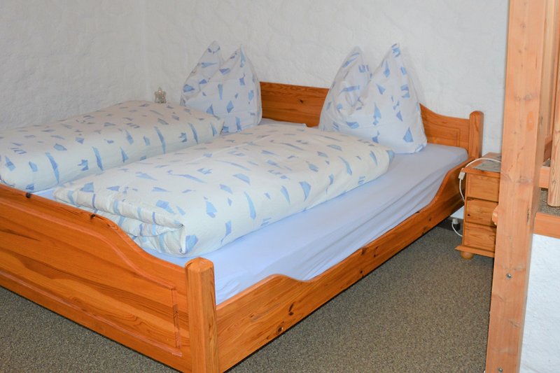 Schlafzimmer mit bequemem Bett, Bettwäsche, Kissen und Kunst.