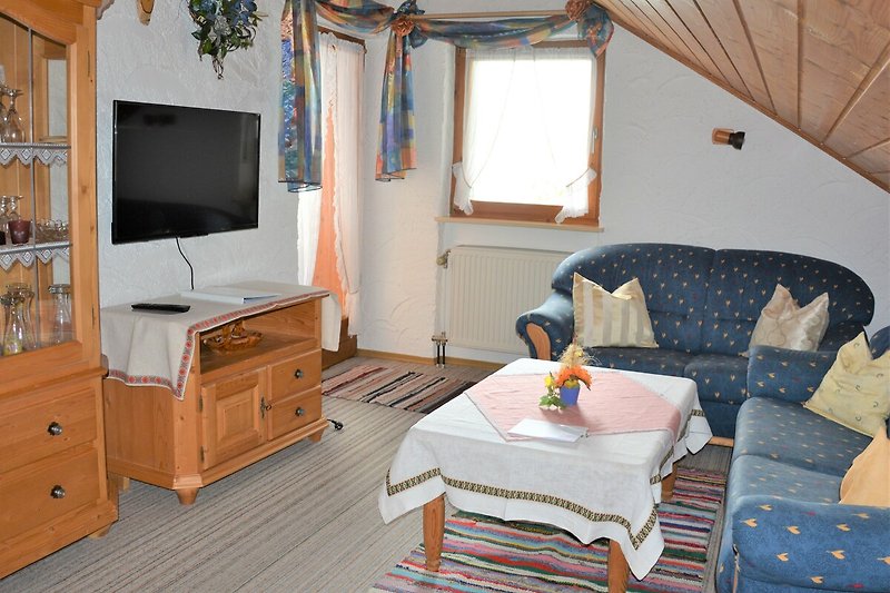 Wohnzimmer mit Fernseher, Couch, Tisch und Schrank. Gemütliche Einrichtung.
