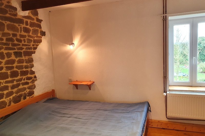 Doppelbett im Schlafzimmer für 3 Personen mit Holzboden und Fenster.