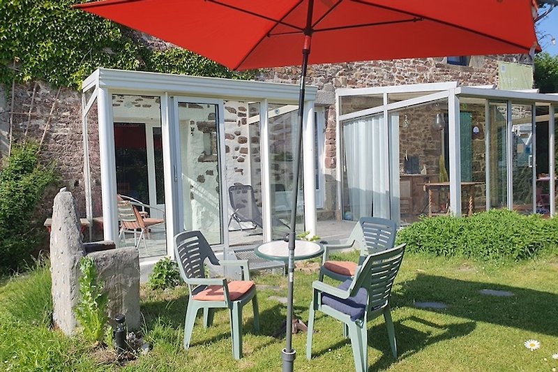 Malve: Einladender Garten mit Sonnenschirm, Tisch und Stühlen.