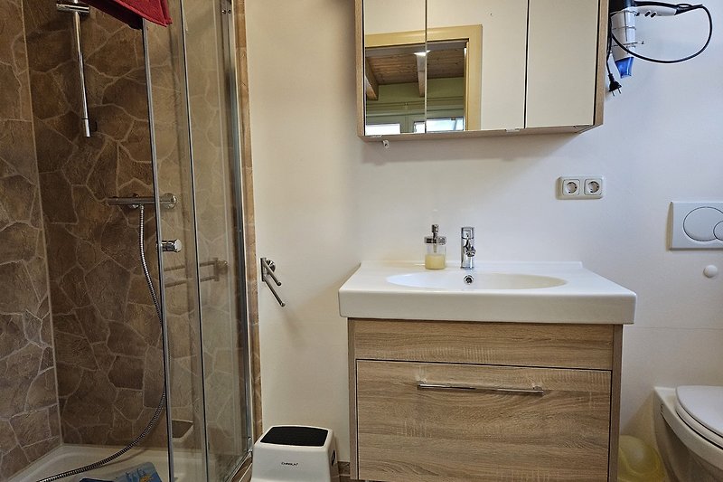 Badezimmer mit Spiegel, Waschbecken und Schrank.