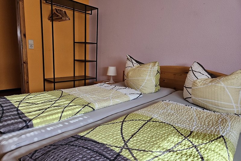 Schlafzimmer mit gemütlichem Bett, Kissen, Decke und Fenster.