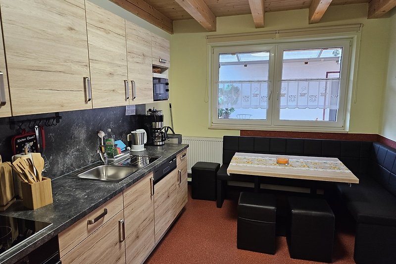 Küche mit Holzmöbeln, Fenster und Spüle.