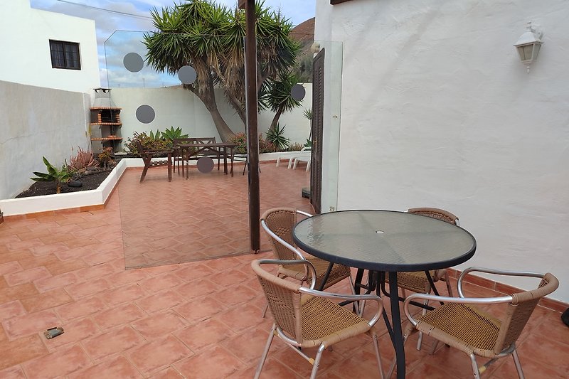Stilvolles Outdoor-Möbelset mit Sonnenschirm und Pflanzen.