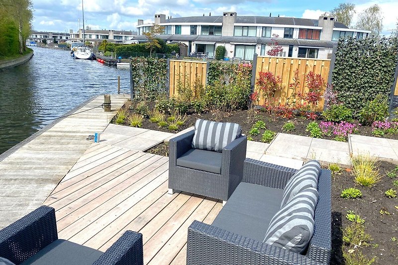 Großer Balkon mit Blick auf den Kanal und gepflegtem Garten.