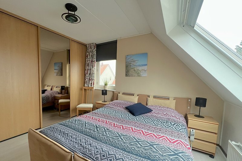 Gemütliches Schlafzimmer mit bequemem Bett, Holzmöbeln und stilvoller Beleuchtung.