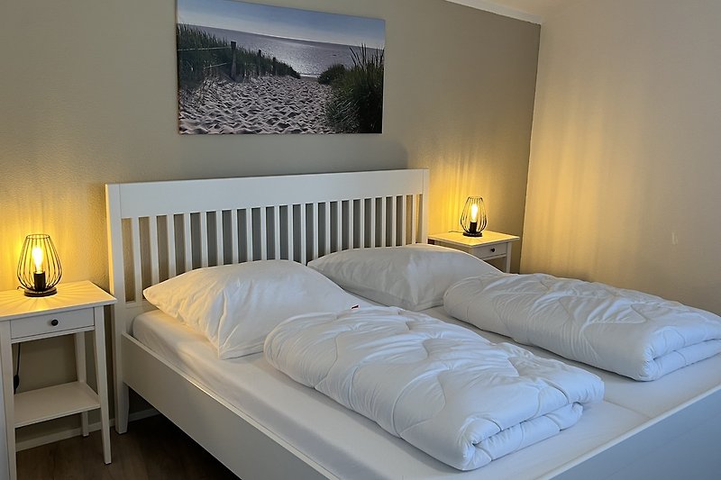 Schlafzimmer mit gemütlichem Bett, Lampen und Holzmöbeln.