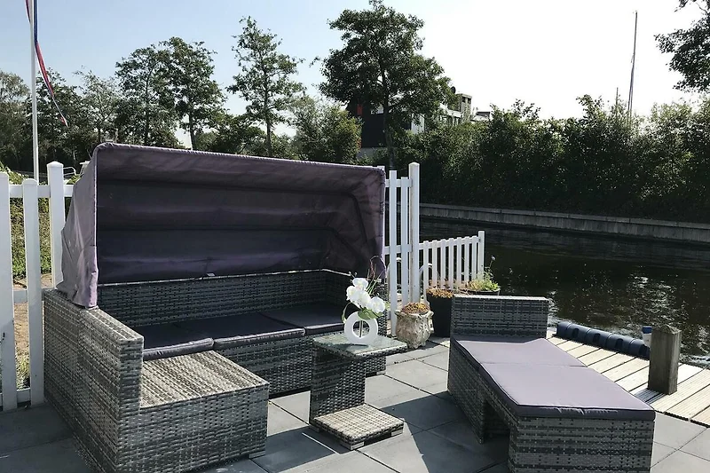 Terrasse mit Outdoor-Möbeln, Blumen und gemütlicher Sitzecke.