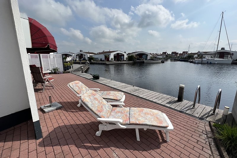 Sonnendeck mit Seeblick, Liegestühlen und Bootsanleger.