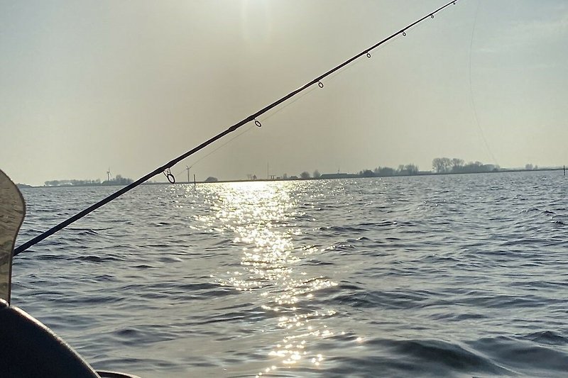 Ein Fischer am ruhigen See mit Angelrute und Boot. Natur pur!