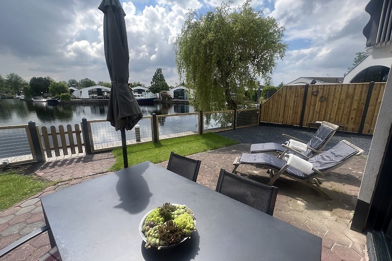 Modernes Haus mit Pflanzen, Wolken und blauem Himmel.