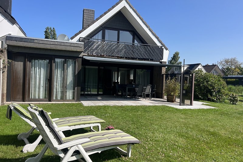 Halbfreistehendes Ferienhaus mit Wiese und sonnige Terrasse.