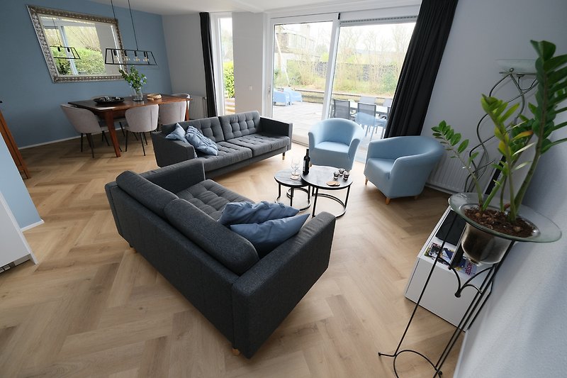 Wohnzimmer mit bequemer Couch, Tisch, Pflanzen und Fenster.