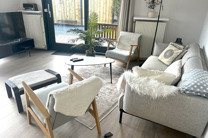Wohnzimmer mit bequemer Couch, Tisch, Pflanze und Lampe.