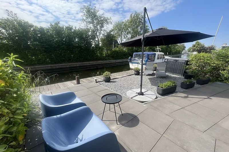 Gemütlicher Garten mit Tisch, Stühlen, Pflanzen und Bäumen.