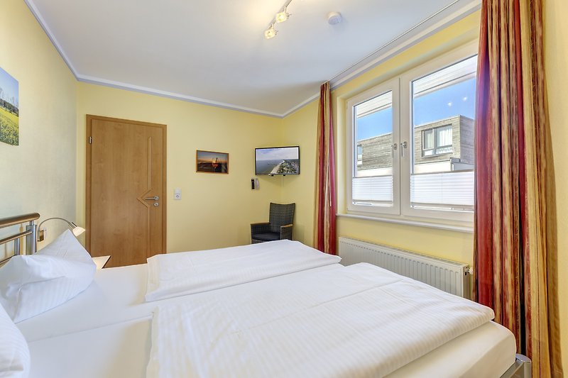 Elegantes Schlafzimmer mit bequemem Doppelbett und Smart TV  32"