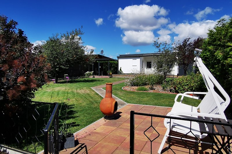 Gemütlicher Garten mit Terrasse, Rasen und Gartenmöbeln.