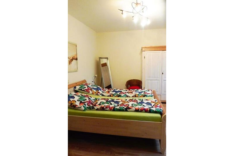 Schlafzimmer mit bequemem Bett, Holzmöbeln und Deckenventilator.