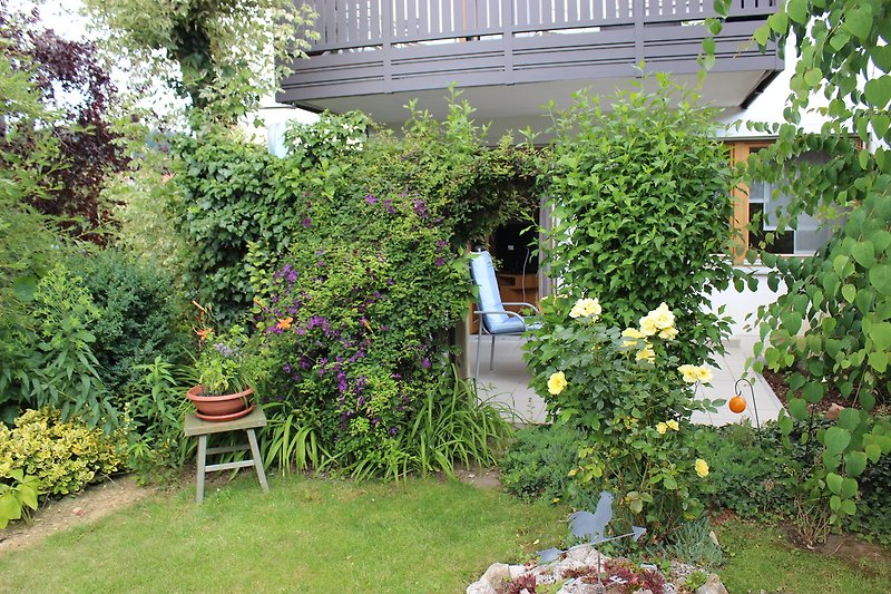 Garten mit Blumen, Sträuchern und Stühlen.