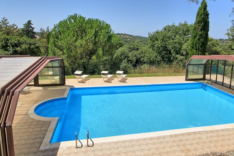 Casa Pancole - Pool mit Liegestühlen, Garten und Blick auf das Haus.