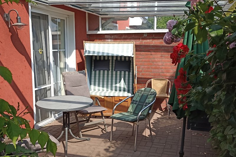 Gemütliche Terrasse mit bequemen Möbeln, Pflanzen und Holzverkleidung.