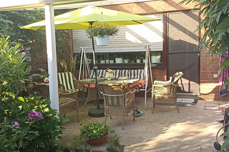 Einladende Terrasse mit bequemen Möbeln, Blumen und Sonnenschirm.