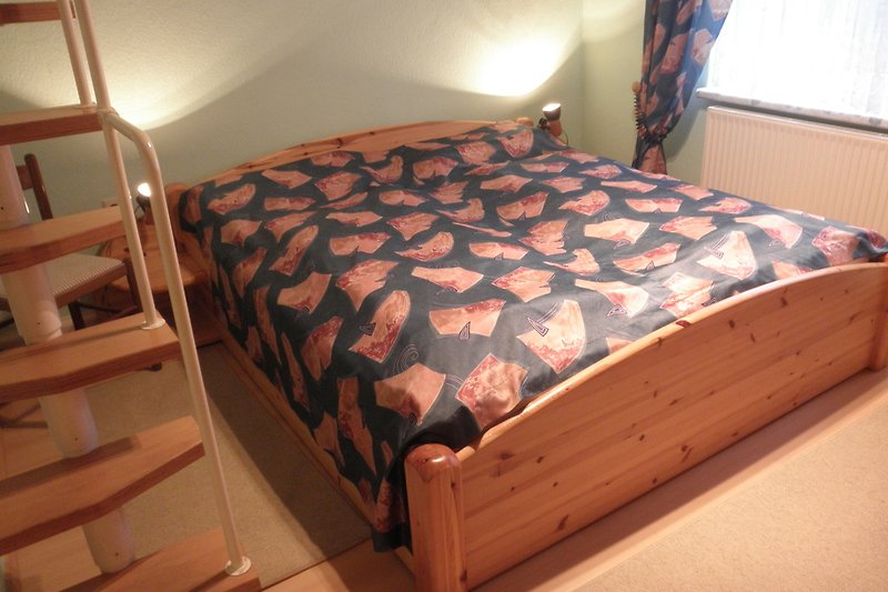 Holz-Bett im Schlafzimmer mit hochwertigen Matratzen, Decken und Kissen.