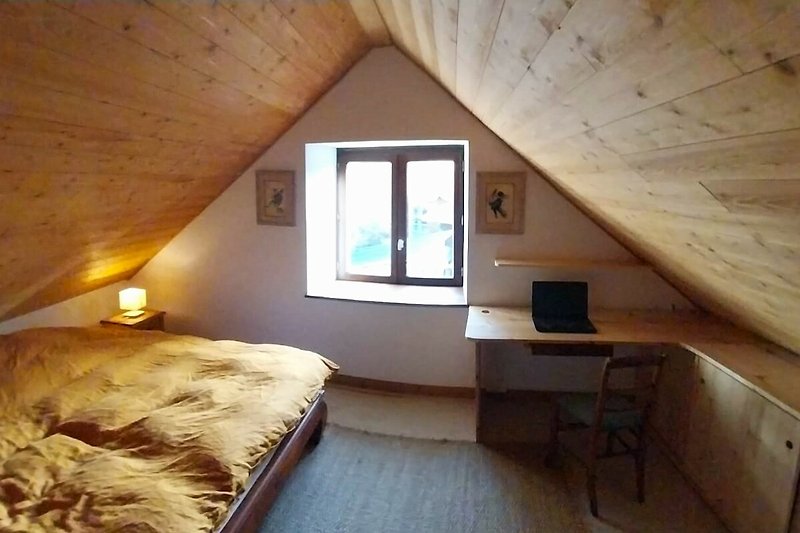 Une chambre confortable avec un lit en bois et une lampe.