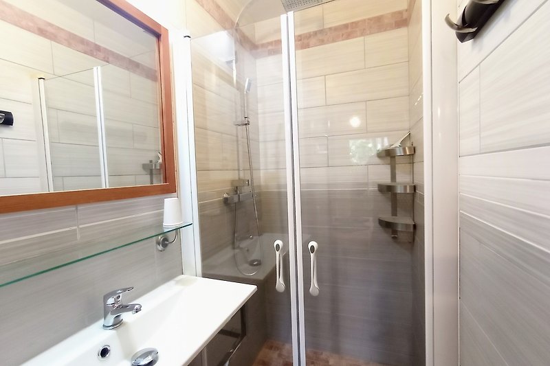 Magnifique salle de bain avec douche en verre et robinetterie moderne.