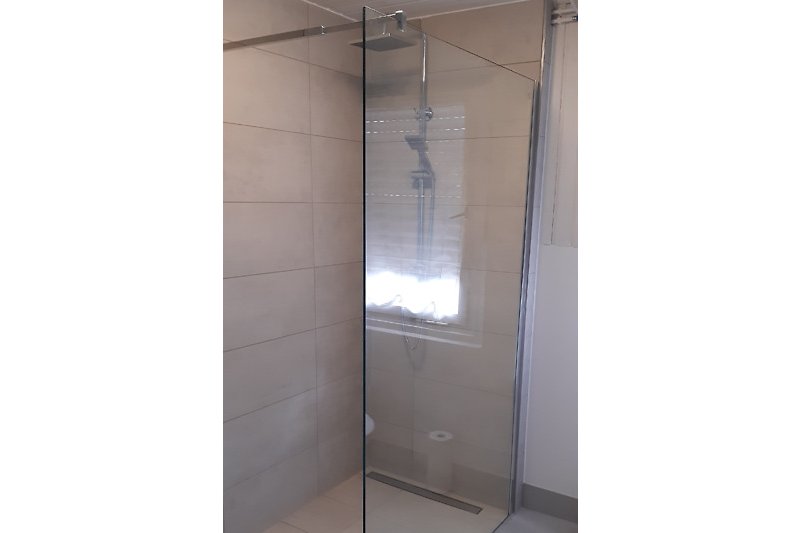 Modernes Badezimmer mit Glasdusche und Metallarmaturen.