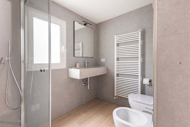Un bagno moderno con specchio, lavabo e arredi in legno.
