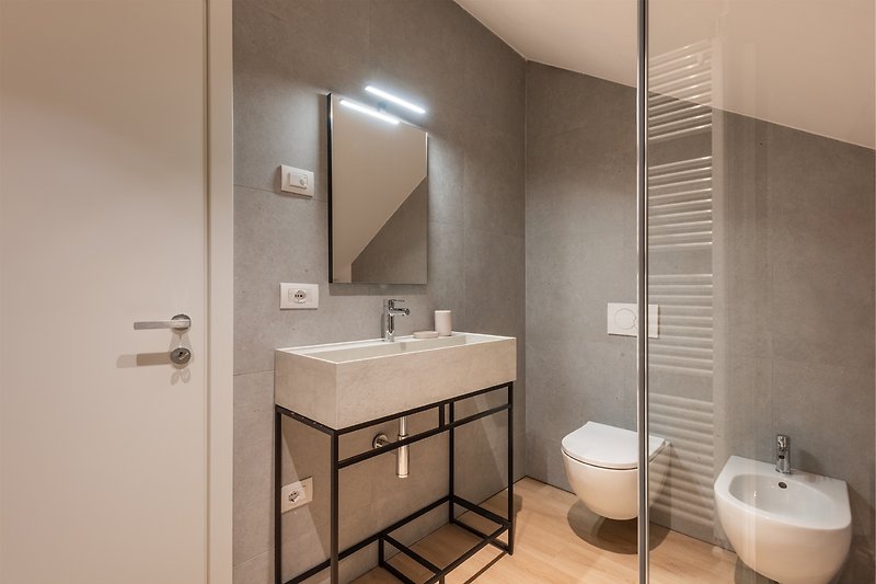 Un bagno moderno con specchio, lavabo e mobili in legno.
