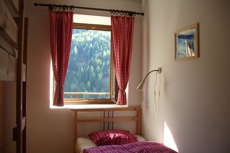 Gemütliches Zimmer mit Stockbett, Einzelbett, Kleiderschrank und Naturblick.