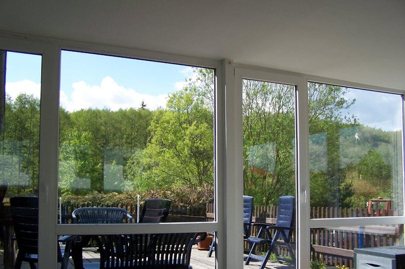 Blick auf die Terrasse mit Gartenmöbel, Sonnenschirmen und Holzkohlegrill