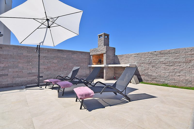 Eine stilvolle Terrasse mit bequemen Möbeln und Sonnenschirm.
