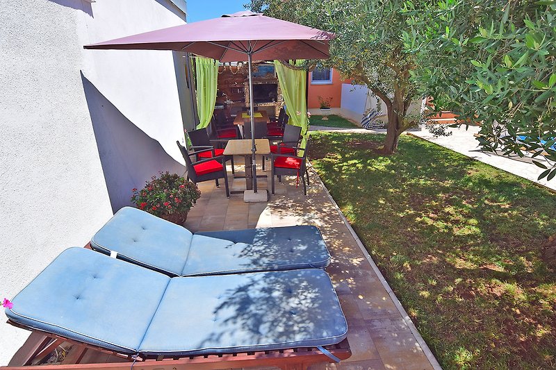 Schattiger Garten mit Outdoor-Möbeln und Sonnenschirm.