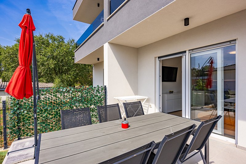 Gemütliche Terrasse mit Holzstühlen, Tisch und grünen Pflanzen.