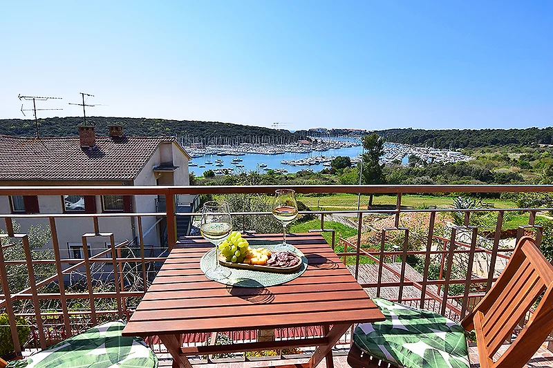 Balkon mit Outdoor-Möbeln und Tisch, umgeben von Pflanzen.