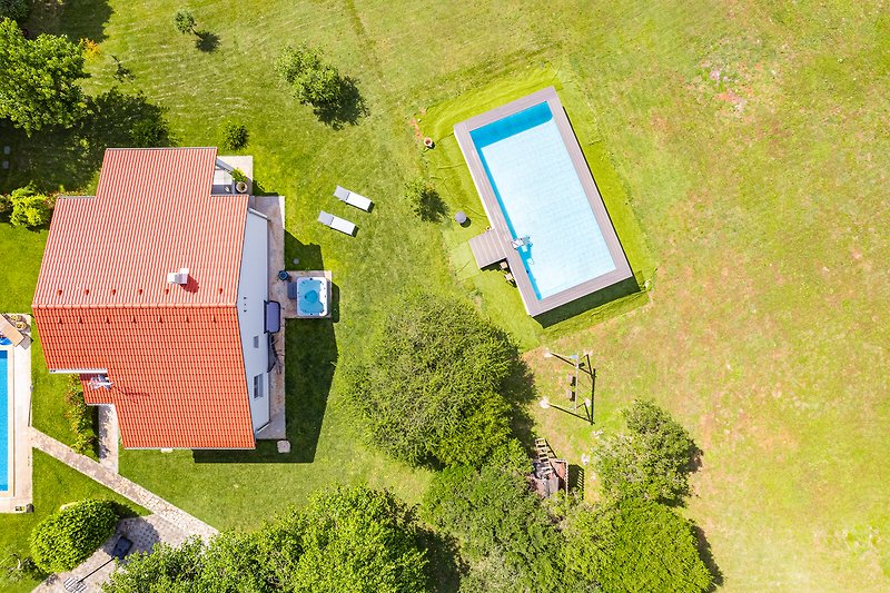 Luftaufnahme: Haus mit Garten, Bäumen und umliegender Landschaft.