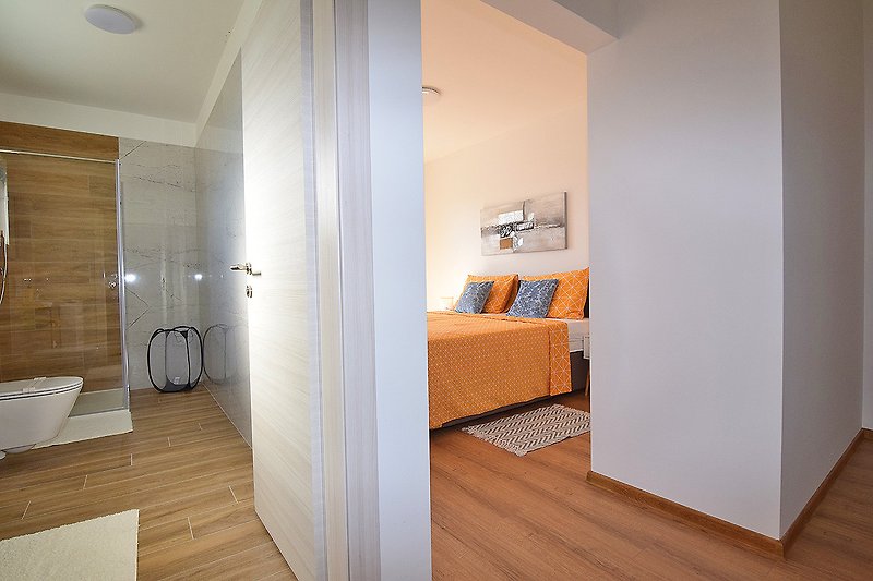 Modernes Schlafzimmer mit stilvollem Bett, Fenster und Holzakzenten.