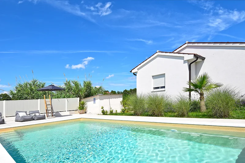 Villa mit Pool, Palmen und Blick auf den blauen Himmel.